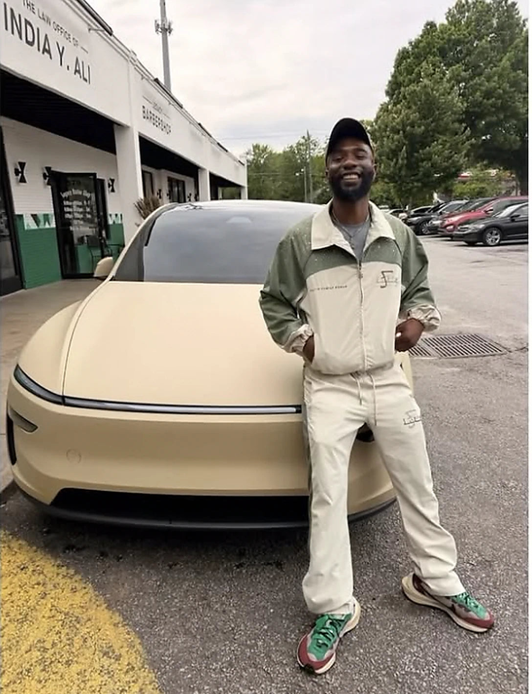 A man in an olive and cream F.LIFE coach jacket beside a tan car