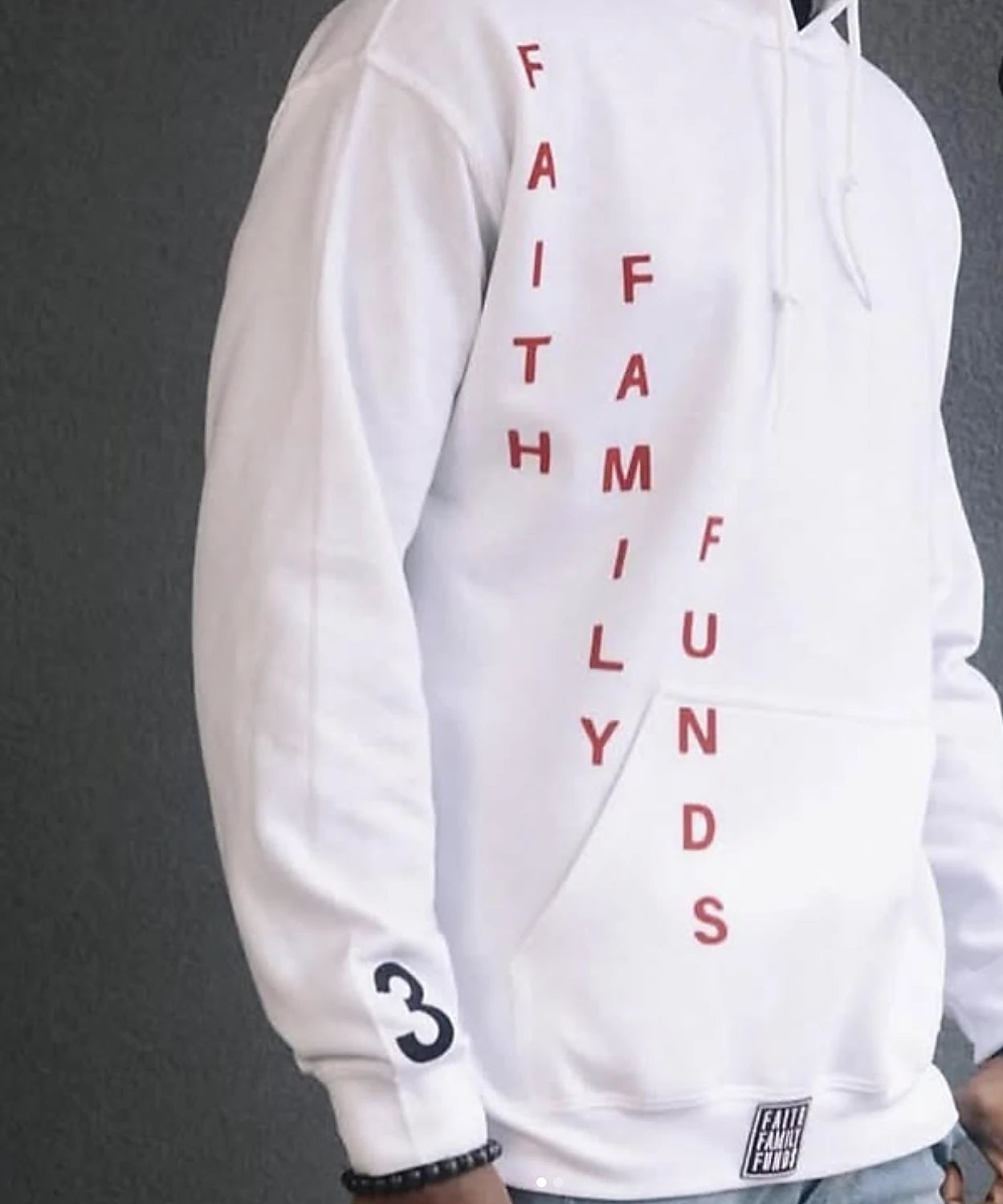 A white hoodie with Faith Family Funds set vertically in red